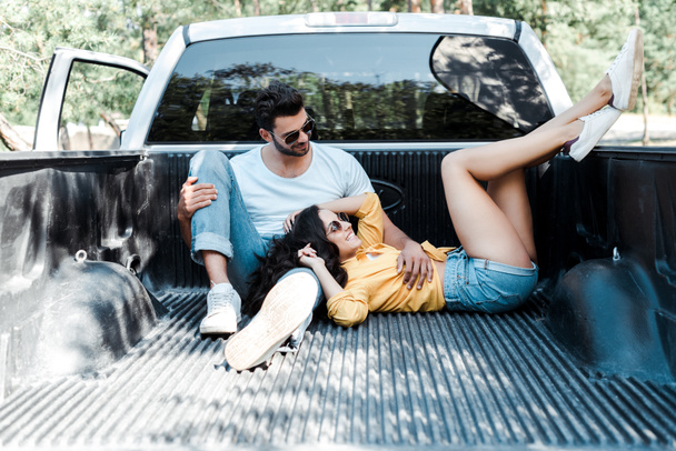 cheerful man in sunglasses sitting in car trunk near girl  - Zdjęcie, obraz