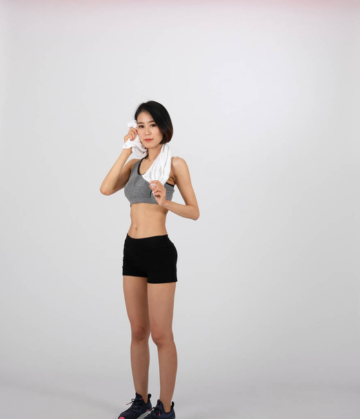 sportliche Fitness-Frau in Sportbekleidung mit Handtuch auf weißem Hintergrund - Foto, Bild