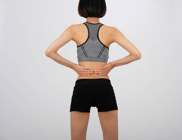 sportliche Fitness-Frau in Sportbekleidung mit Rückenschmerzen auf weißem Rücken - Foto, Bild