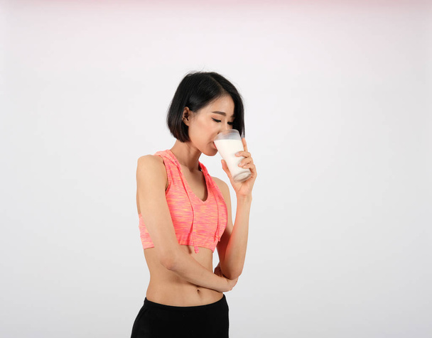 sporty fitness woman in sportswear drinking milk on white backgr - Photo, Image