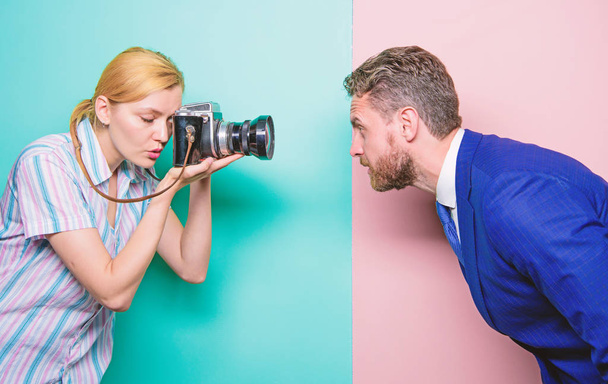 Taking a portrait. Businessman posing in front of female photographer. Fashion shooting in photo studio. Pretty woman using professional camera. Photographer shooting male model in photo studio - Photo, Image