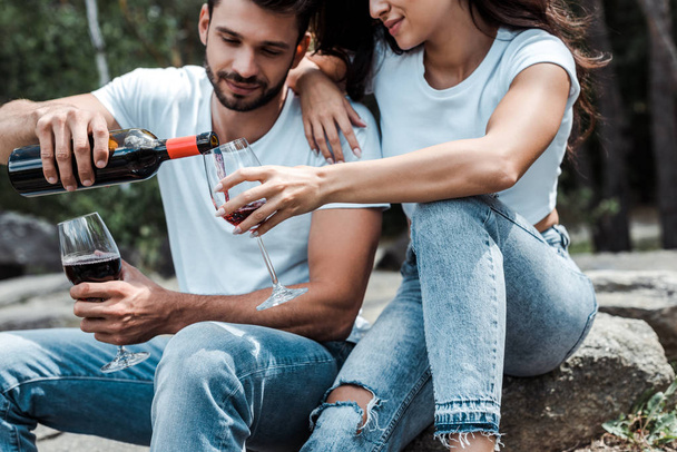 handsome man pouring red wine from bottle near young woman  - Foto, immagini
