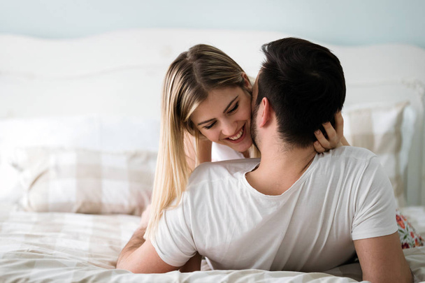 Portrait of young attractive loving couple in bedroom - 写真・画像