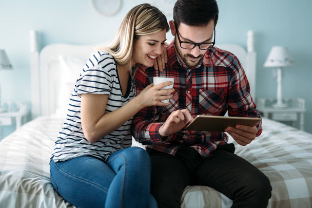 Young happy couple using digital tablet in bedroom - Foto, afbeelding