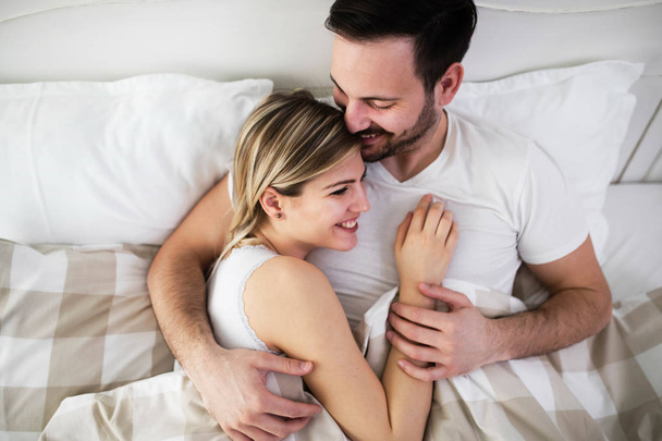 Beautiful woman and attractive man lying on bed together - 写真・画像