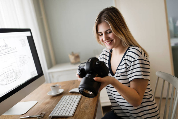 Picture of young beautiful female designer holding camera - Foto, Imagen