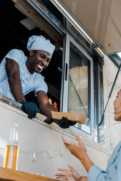 アジアの顧客にカートンプレートを与える幸せなアフリカ系アメリカ人男性の低角度図  - 写真・画像