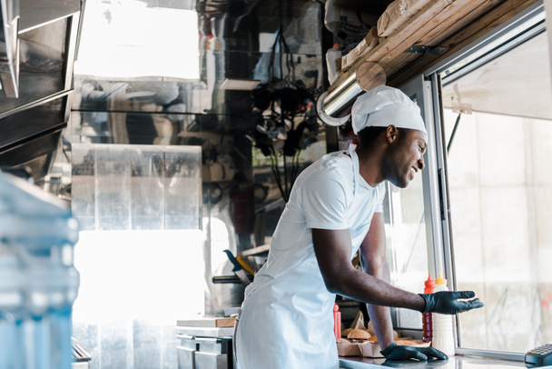 selective focus of cheerful african american chef smiling in food truck  - Photo, Image