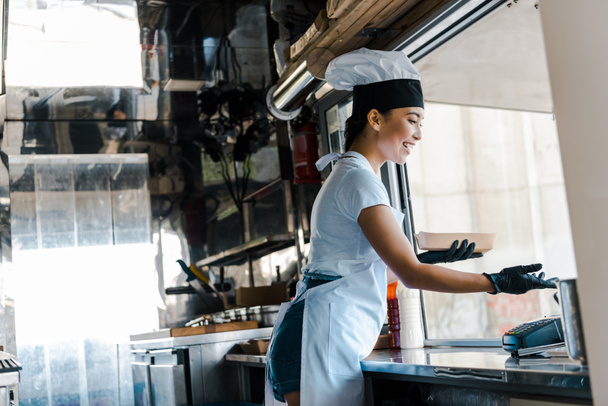 happy asian woman in latex gloves holding carton plate in food truck  - Photo, Image