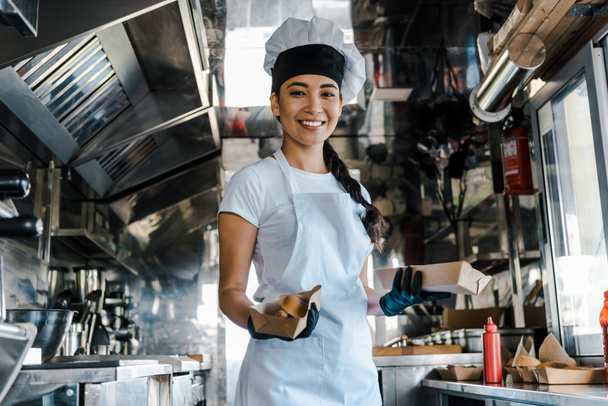 happy asian chef holding carton plates in food truck  - Photo, Image