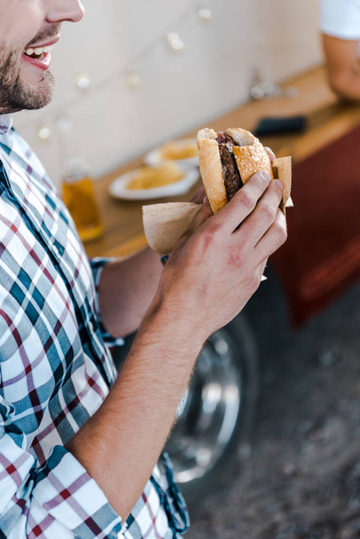 cropped view of happy man holding tasty burger  - Foto, Bild