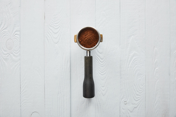 Top view of portafilter with coffee on white wooden surface - Photo, Image
