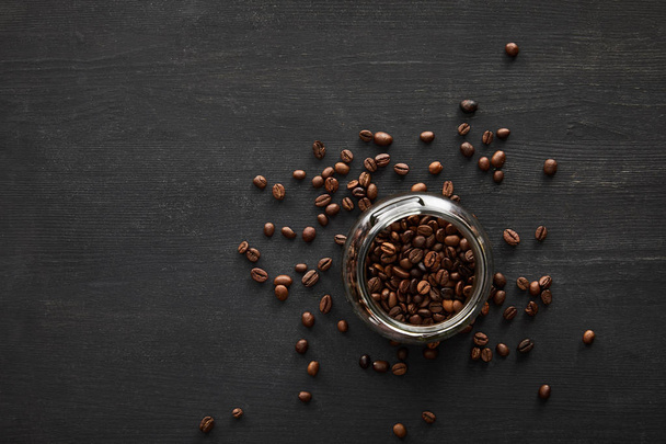 暗い表面にコーヒー豆で満たされたガラス瓶のトップビュー - 写真・画像