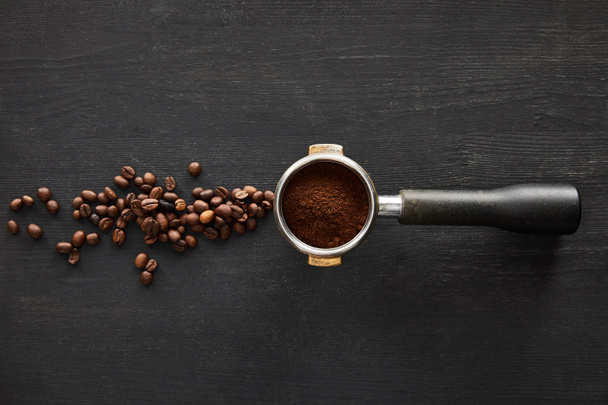Widok z góry kolby z kawą na ciemnym drewnianej powierzchni z rozrzuconych ziaren kawy - Zdjęcie, obraz