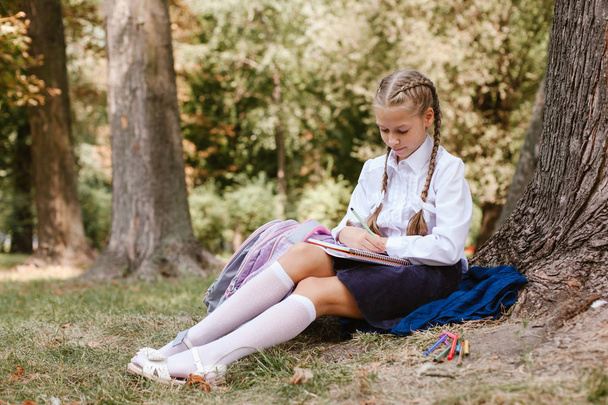 eine Schülerin gibt Unterricht in einem Park unter einem Baum .eine Schülerin sitzt unter einem Baum im Park - Foto, Bild