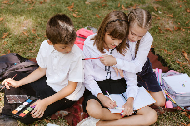 Dzieci szkolne wykonują pracę domową w przyrodzie. Schoolchildren bawić  - Zdjęcie, obraz