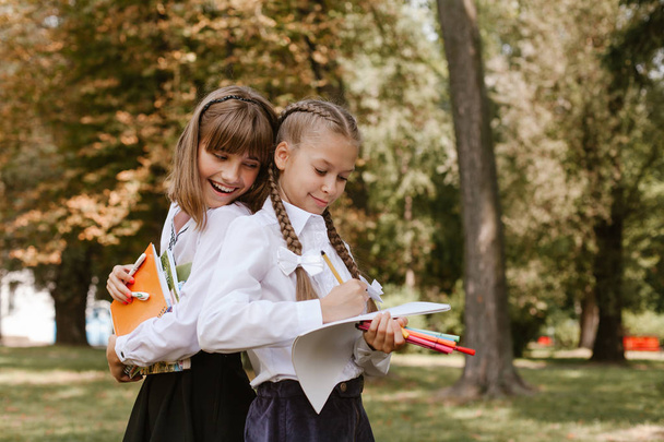 zurück zur Schule. Schulkinder machen Hausaufgaben in der Natur.. Schulmädchen haben Spaß im Park - Foto, Bild