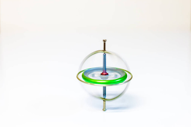 Een draaiende speelgoed gyroscoop geïsoleerd op een witte achtergrond - Foto, afbeelding