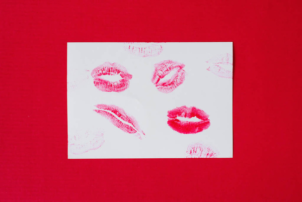 Handmade postcard with red lipstick lip prints on red background - Foto, afbeelding