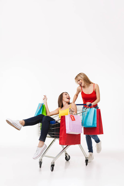 Full length of two cheerful young girl shopping together - Photo, image
