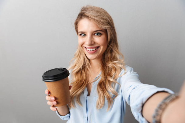 Photo of adorable blond businesswoman smiling and holding paper  - Фото, зображення