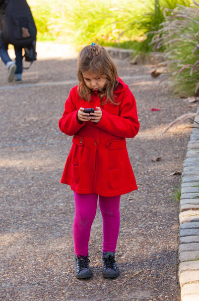 Girl in red with mobile in park - Foto, Imagen