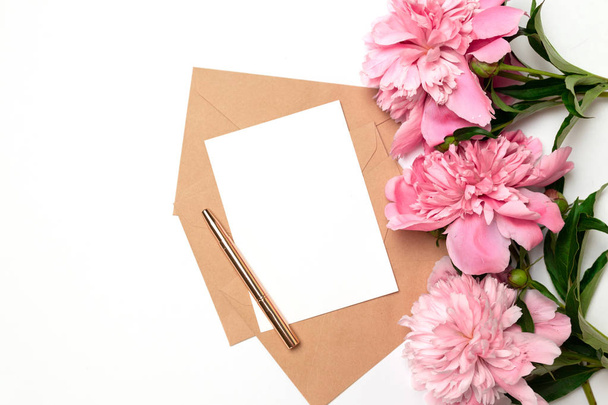 Wedding invitations, craft envelopes, pink flowers and green leaves on a white background - Φωτογραφία, εικόνα