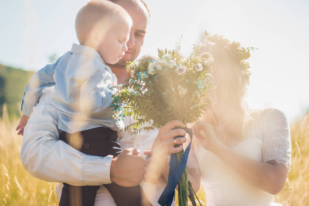 Happy family with kid walking together in wheat field on warm and sunny summer day. Soft focus. - Valokuva, kuva