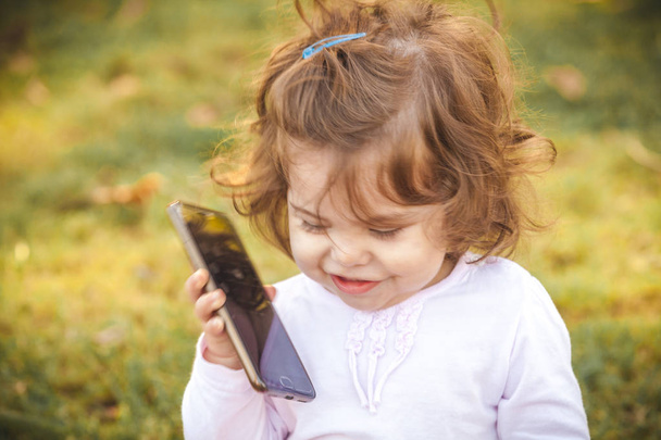 baby met mobiel in park - Foto, afbeelding