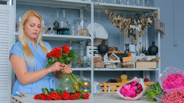 Цветочница делает букет в цветочном магазине - Фото, изображение