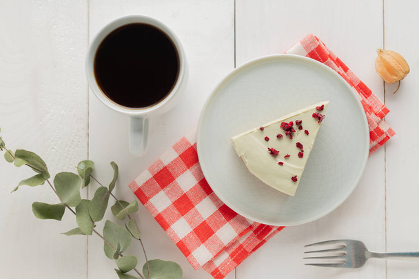 Piece of cheesecake on gray plate on kitchen spatula and cup of coffee on background - Valokuva, kuva