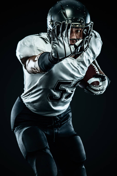 American football sportsman player in helmet isolated run in action on black background. Sport and motivation wallpaper. Team sports, - Фото, изображение