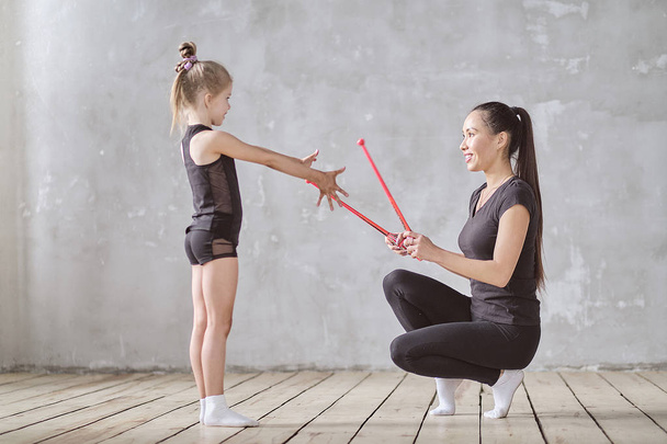 Витончена маленька дівчинка балерина стоїть на руках і тягнеться з вчителем в танцювальній студії
 - Фото, зображення