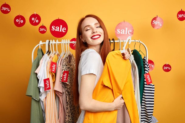 positive girl wants to buy stylish clothes , hugging yellow sweater - Foto, immagini