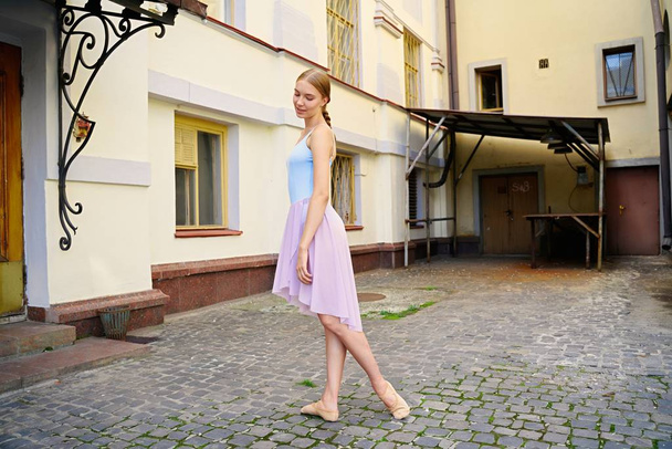 Young and graceful ballerina performing on the street - Фото, изображение