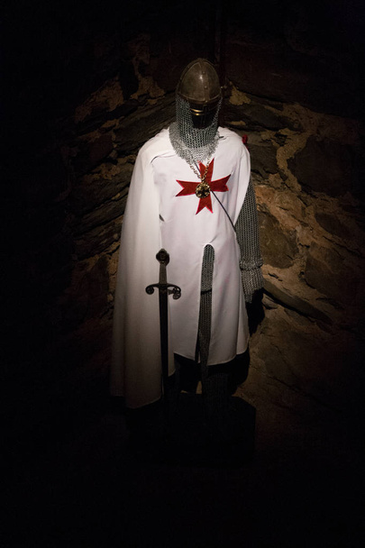 Kostuum van een Tempeliers met zwaard in het donker met stenen achtergrond - Foto, afbeelding