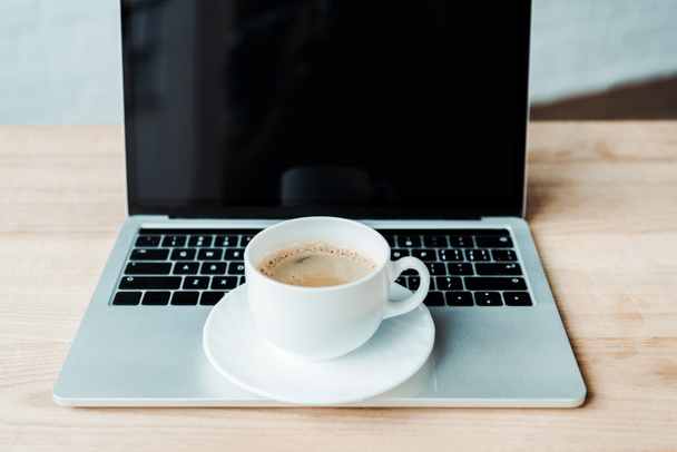 filiżanka kawy na laptopie z pustym ekranem w biurze  - Zdjęcie, obraz