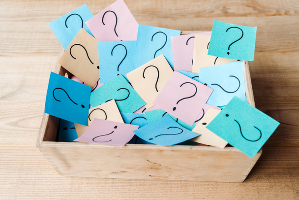 overhead view of sticky notes with question marks in wooden box on desk  - Foto, Imagem