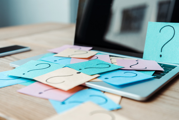 selective focus of sticky notes with question marks on laptop with blank screen  - 写真・画像