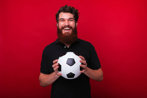 Foto del partidario barbudo, sosteniendo una pelota de fútbol mientras mira
  - Foto, Imagen