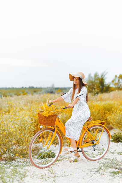 Styl Vintage zdjęcie młodej kobiety, na żółtym rowerze, noszenie - Zdjęcie, obraz