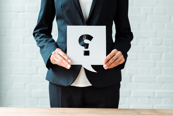 cropped view of woman holding speech bubble with question mark while standing in office  - Photo, Image