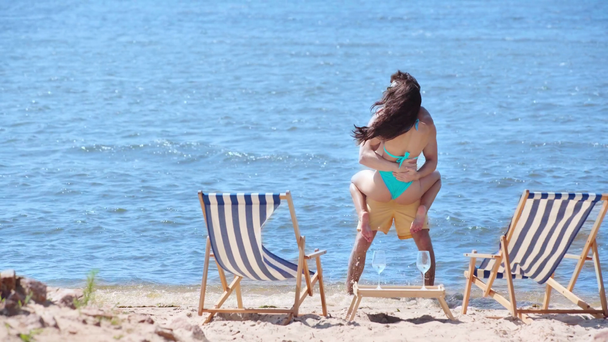 ευτυχισμένος νέος άνθρωπος κρατώντας στα χέρια ελκυστική φιλενάδα, ενώ έχει τη διασκέδαση στην παραλία - Πλάνα, βίντεο