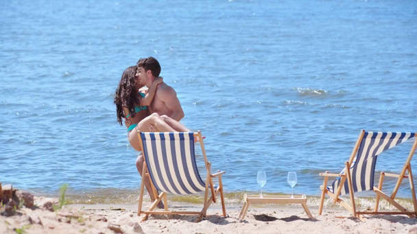 gelukkige jonge man die vriendin op handen houdt terwijl ze samen op het strand rust - Video