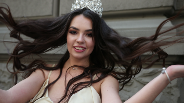 brunette girl in a light dress with a deep neckline, with a crown, posing - Footage, Video