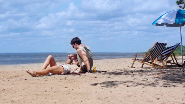 sahilde dinlenirken mutlu genç çift sarılma ve konuşma  - Video, Çekim