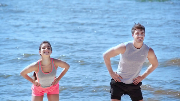 jovem, alegre homem e mulher exercitando na praia juntos
 - Filmagem, Vídeo
