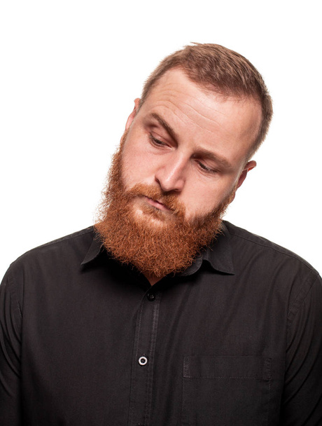 Portrait of a young, chubby, redheaded man in a black shirt making faces at the camera, isolated on a white background - Photo, Image