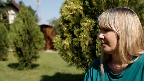 Blondýnka sedící na trávníku obléká sluneční brýle - Záběry, video
