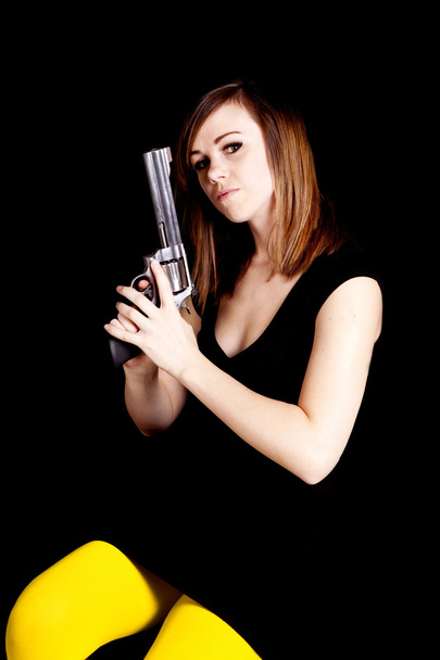 A woman holding a gun on a black background - Photo, Image